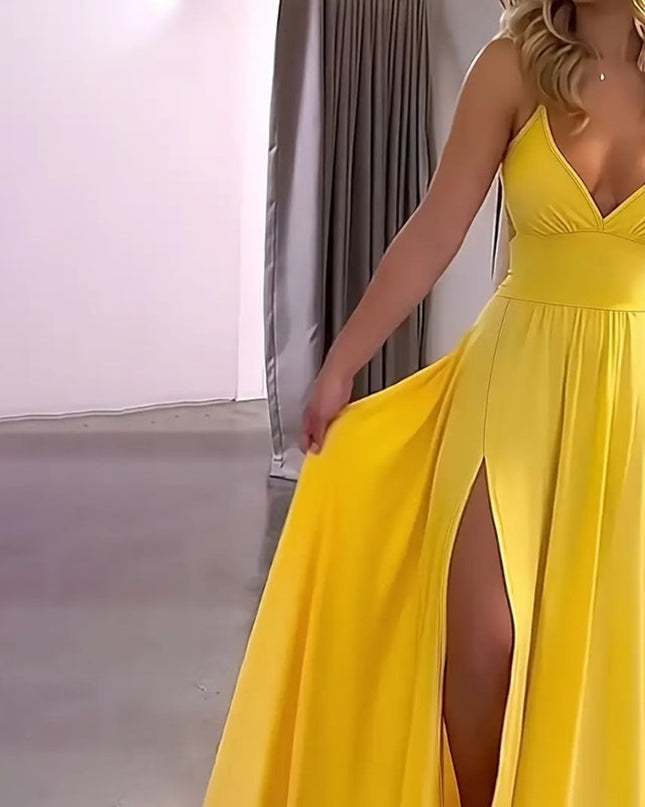 Woman wearing a yellow evening gown with a slit, standing indoors.
