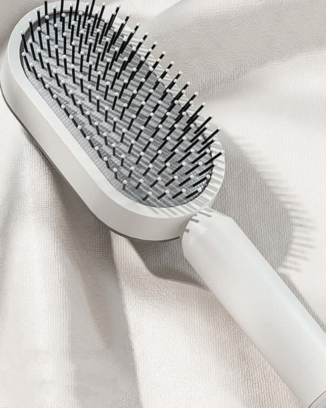 White hairbrush with black bristles on a light fabric background