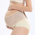 Pregnant woman wearing a beige maternity support belt on a white background