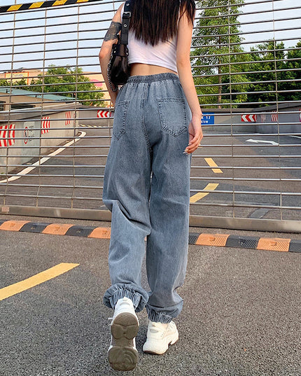 Person wearing light blue jeans and white sneakers standing in a parking lot.