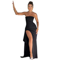 Woman in a black strapless gown with a high slit standing in a doorway.