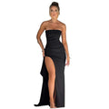 Woman wearing a black strapless gown with a high slit in a room.