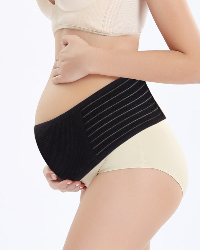 Pregnant woman wearing a black maternity support belt on a white background