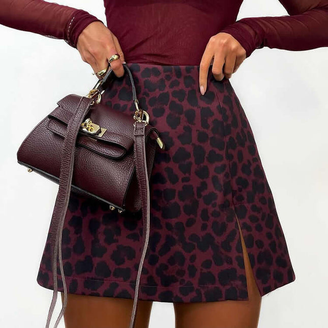 Person wearing a burgundy top and leopard print skirt holding a matching handbag.