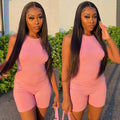 Woman in a pink outfit standing outdoors with greenery in the background
