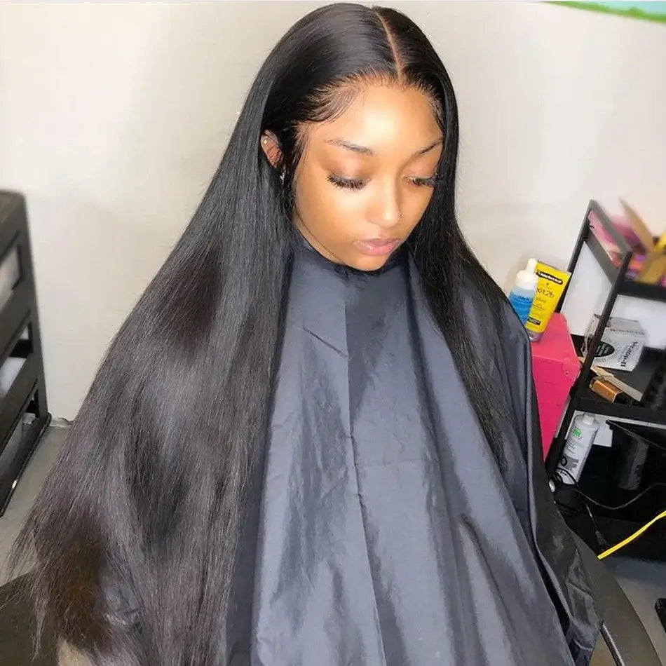 Woman with long straight hair wearing a black salon cape, sitting in a chair.