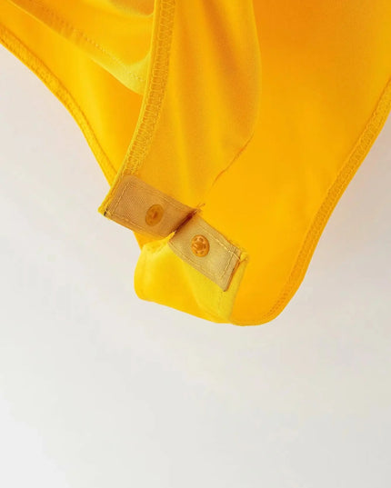 Close-up of a yellow garment with a button on a light gray background
