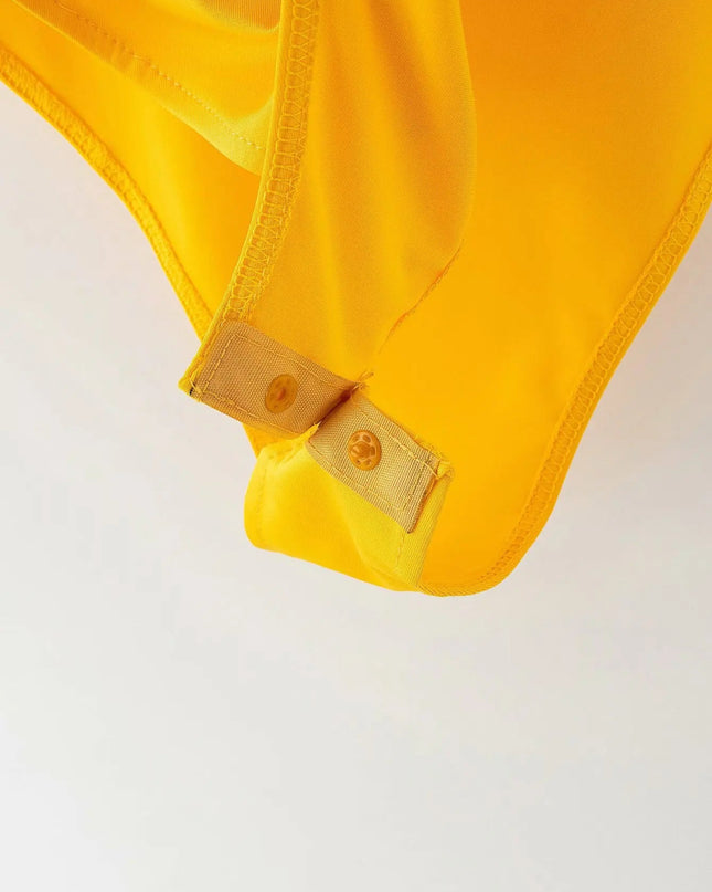 Close-up of a yellow garment with a button on a light gray background