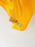 Close-up of a yellow garment with a button on a light gray background