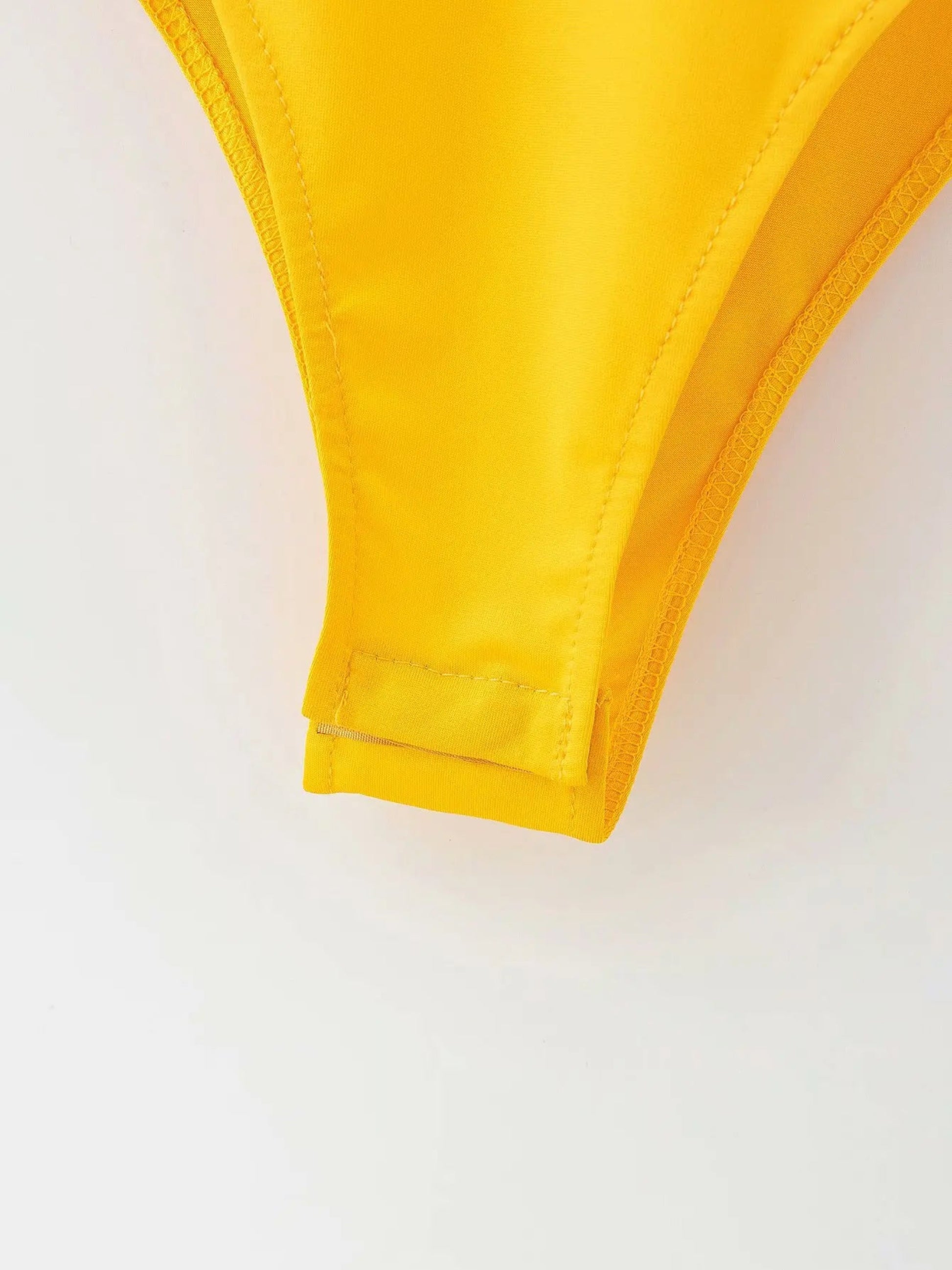 Close-up of a yellow bikini top on a white background