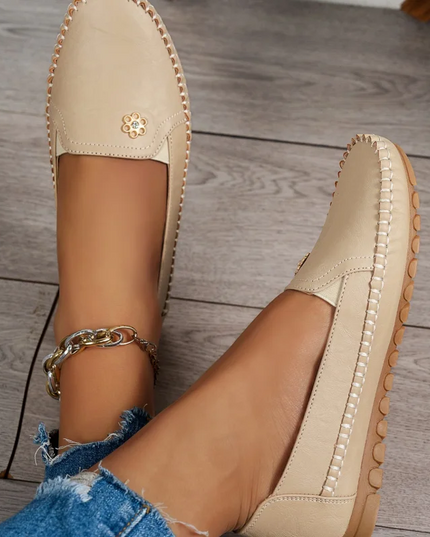 Comfortable women's loafers with laser stitch detail, casual flat slip-on shoes showcased on a wooden floor.