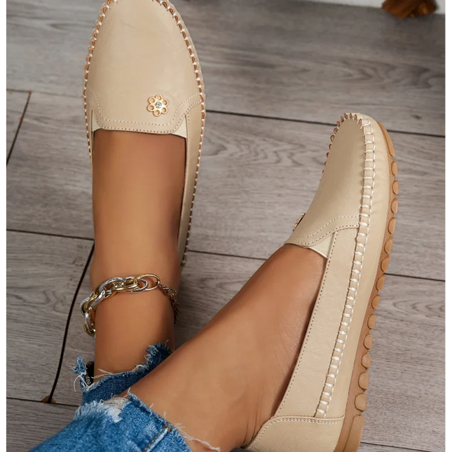 Comfortable women's loafers with laser stitch detail, casual flat slip-on shoes showcased on a wooden floor.