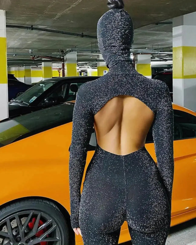 Person wearing a black textured outfit with an open back standing next to a yellow car in a parking garage.