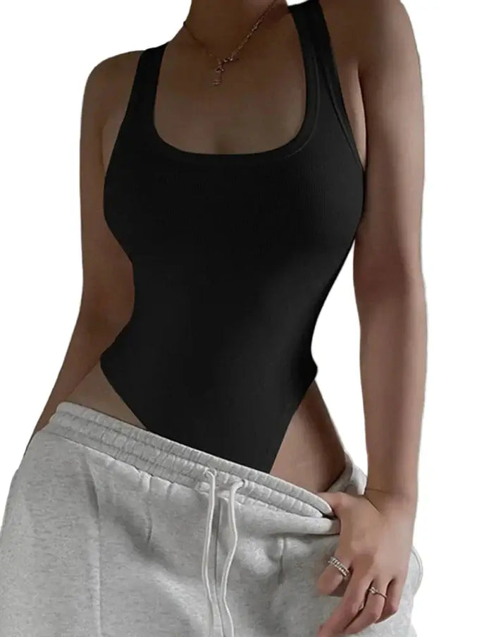 Person wearing a black bodysuit and gray sweatpants against a neutral background