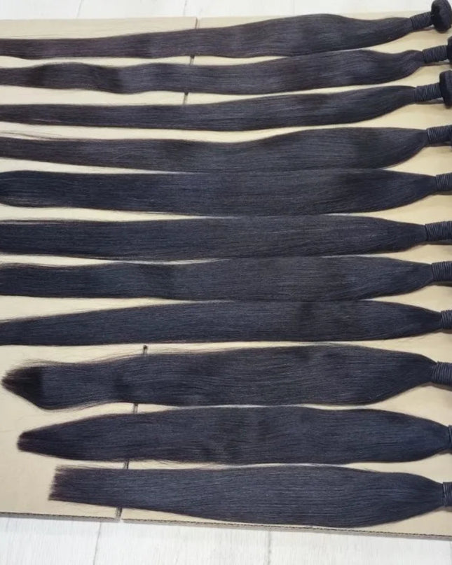 Row of black hair extensions on a beige surface with labels indicating size.