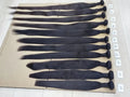 Row of black hair extensions on a beige surface with labels indicating size.