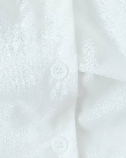 Close-up of buttons on a white cotton linen summer dress showcasing fabric texture and detail.