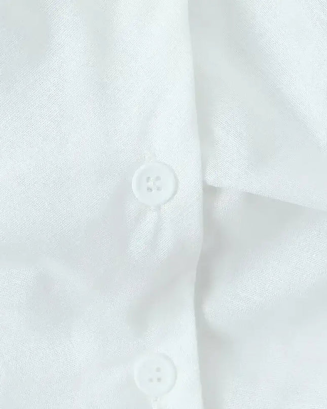 Close-up of buttons on a white cotton linen summer dress showcasing fabric texture and detail.