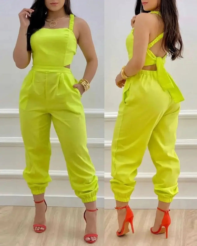 Woman wearing a bright yellow jumpsuit with red high heels in front of a white wall.