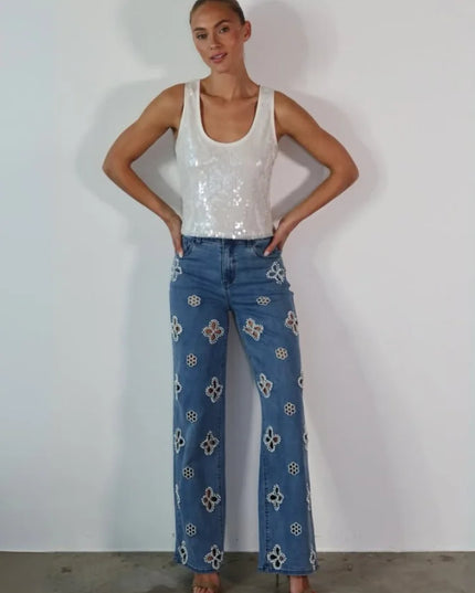Model wearing casual hollow out women’s jeans with floral designs and a sequined top.