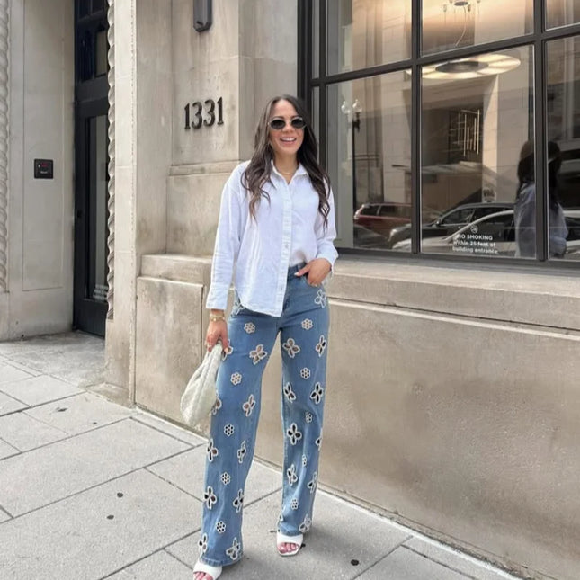 Casual hollow out women’s jeans paired with a white shirt, showcasing a trendy urban style in front of a chic building.