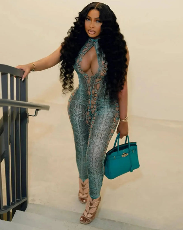 Woman in a patterned jumpsuit holding a blue handbag against a neutral background