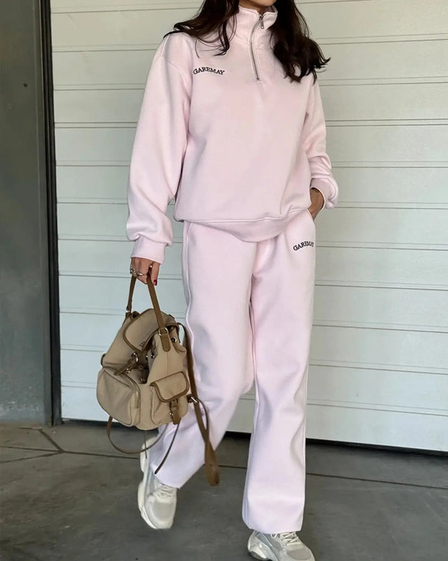 Person wearing a pink tracksuit with 'GAP' branding, holding a beige backpack.