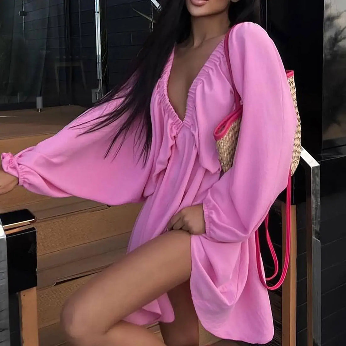 Model wearing a pink deep V-neck pleated dress with long sleeves and a stylish bag, showcasing a sexy retro vibe.