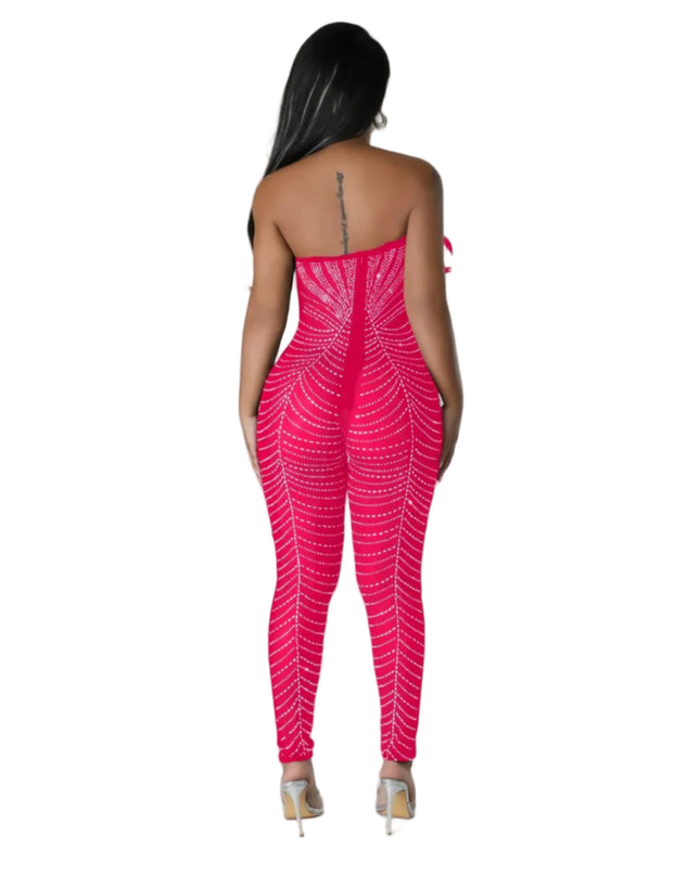 Woman wearing a bright pink strapless jumpsuit with a geometric pattern on a gray background