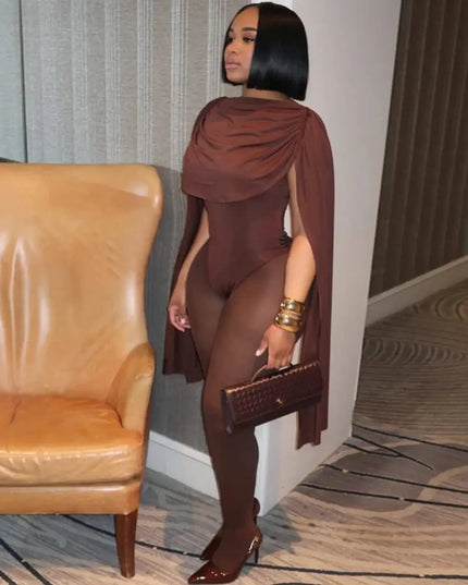 Woman in a brown outfit standing next to a tan leather couch in a room with a textured wall.