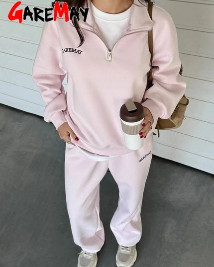 Person wearing a pink 'GAREMAY' tracksuit holding a coffee cup.