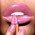 Close-up of a person applying pink glittery lipstick to their lips.