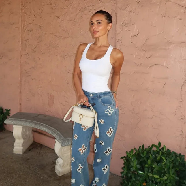 Casual hollow out women’s jeans loose straight with floral design, styled with a white tank top and handbag.