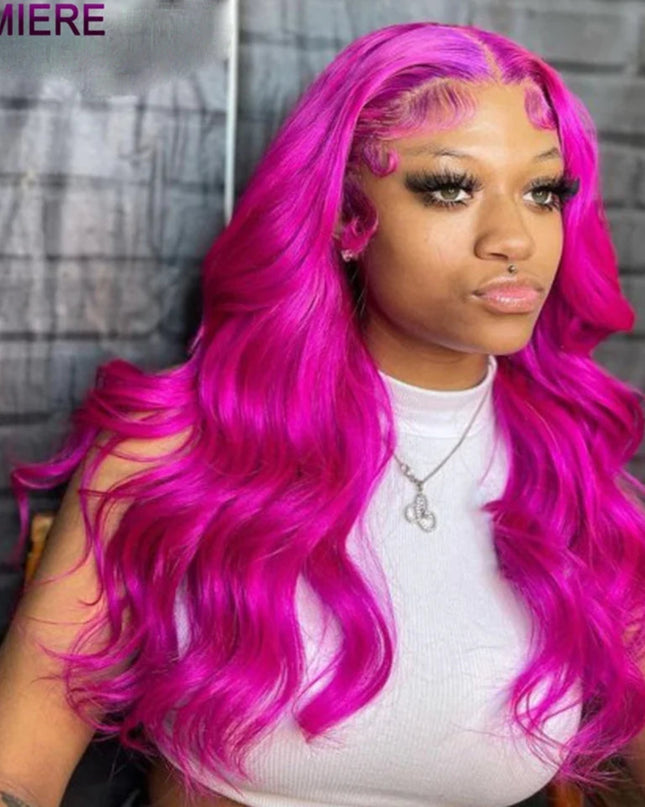 Person with vibrant pink hair styled in loose waves, wearing a white top against a gray brick wall.