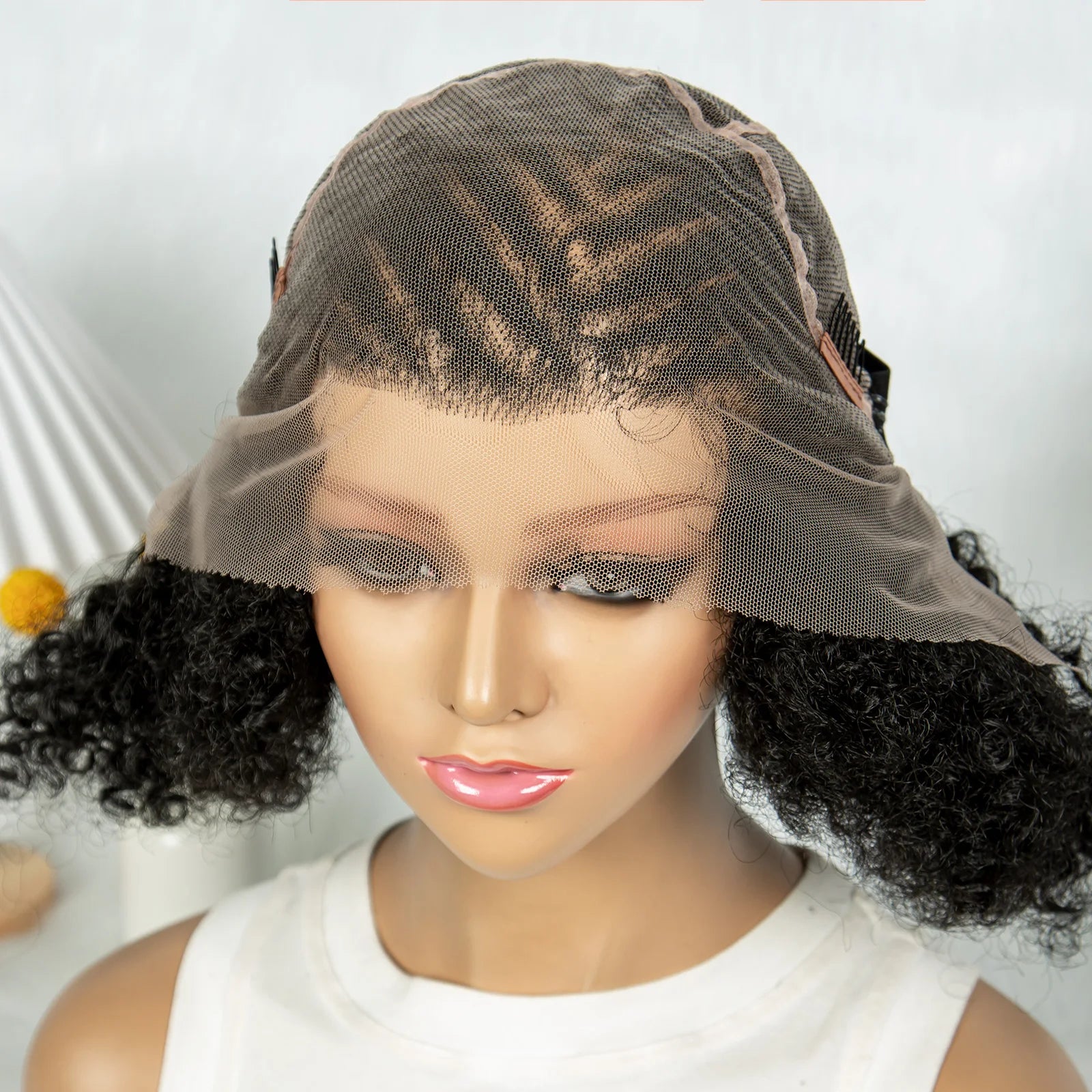 Mannequin head with a black curly wig on a white background