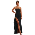 Woman wearing a black strapless gown with a high slit on a white background