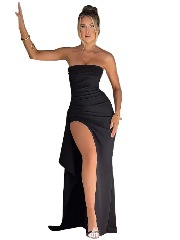 Woman in a black strapless dress with a high slit standing indoors.