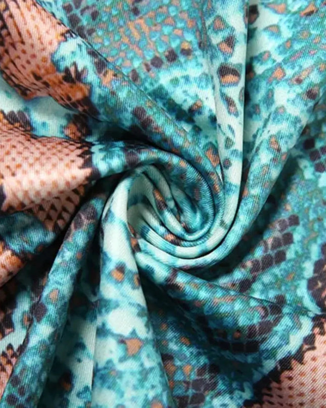 Close-up of fabric with a snake print pattern in teal, brown, and black.