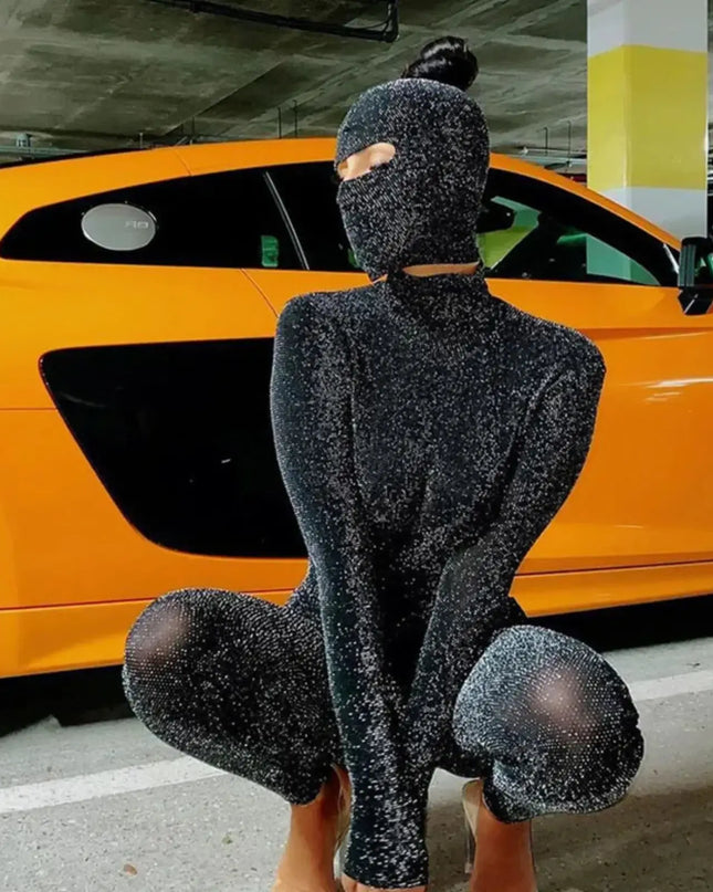 Person wearing a black glittery outfit in front of an orange car.