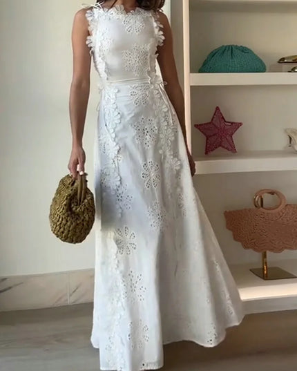 Woman wearing a white lace dress holding a woven bag indoors.