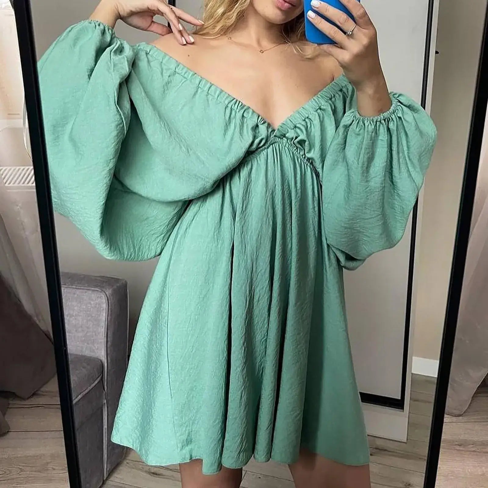 Model wearing a mint green off-shoulder dress with puffed sleeves, showcased in a mirror reflection.