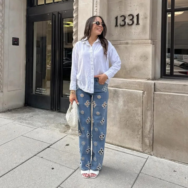 Casual hollow out women’s jeans worn by a woman outside a building, showcasing a trendy urban look.