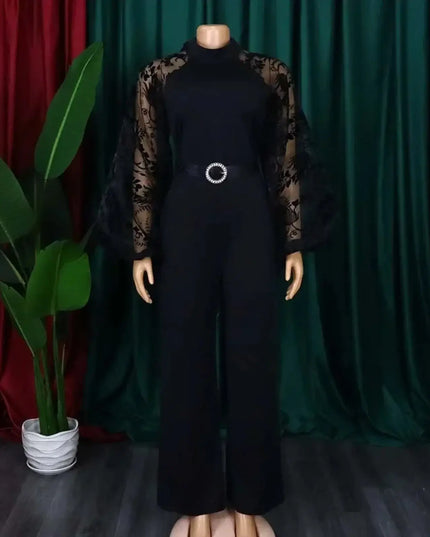 Black jumpsuit with sheer sleeves on a mannequin against a green curtain background