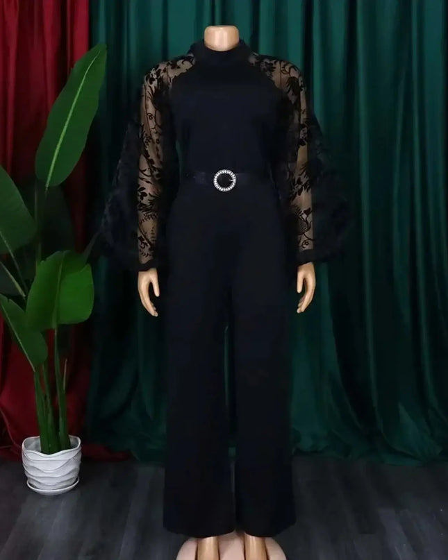 Black jumpsuit with sheer sleeves on a mannequin against a green curtain background