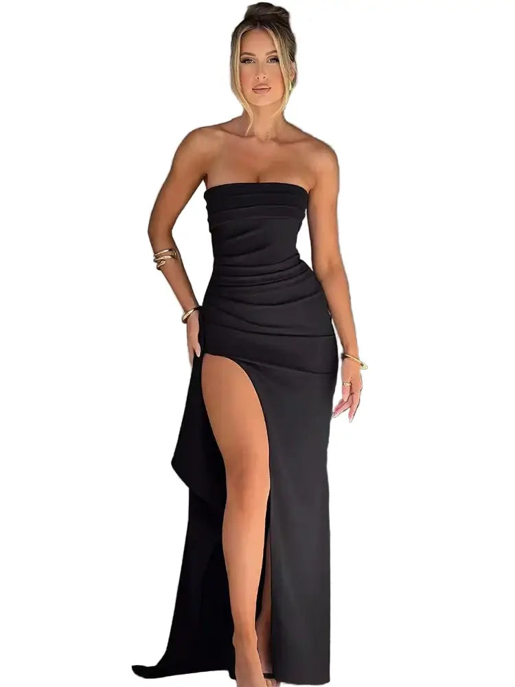 Woman in a black strapless dress with a high slit standing indoors.