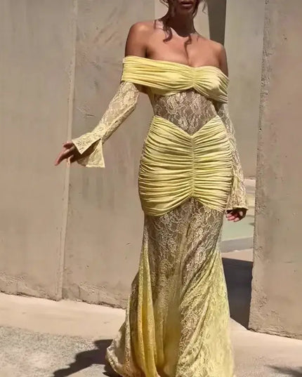 Woman wearing a yellow lace dress against a plain wall.