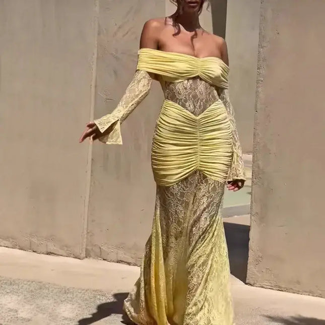 Woman wearing a yellow lace dress against a plain wall.