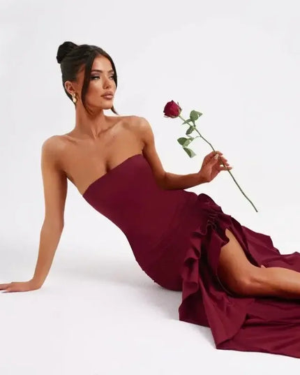 Sexy strapless summer dress in burgundy worn by a model holding a rose, showcasing an elegant irregular design.