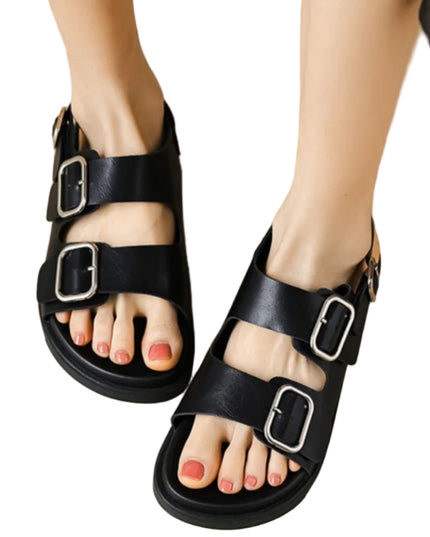 Black sandals with buckles worn by a person on a beige background
