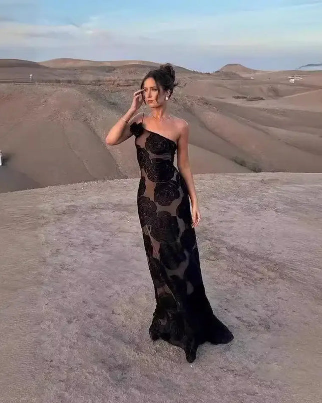 Oligai one shoulder elegant dress in black mesh with floral design, perfect for weddings and parties, on a desert backdrop.